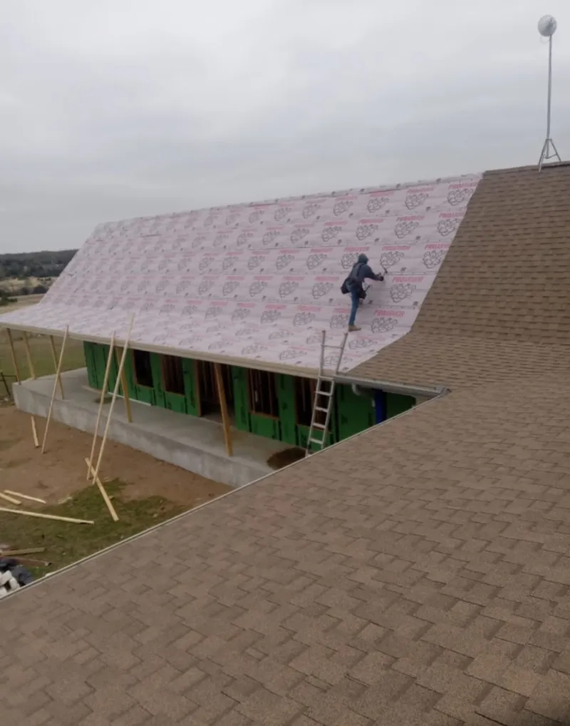 Worker preparing underlayment for a metal roof installation in Beaver Dam